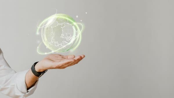 Mão segurando uma esfera luminosa representando sustentabilidade